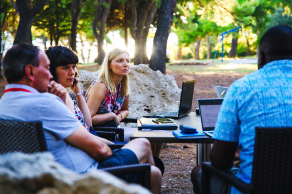 Postdocs and mentors sit outside at the Summer School and converse in the warm surroundings of the venue